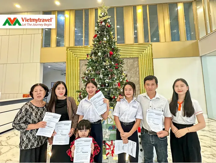 Gia đình khách hàng cầm giấy tờ visa cùng chuyên viên Vietmytravel
